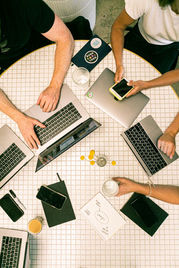 Vue d’ensemble d’une équipe qui collabore avec des ordinateurs portables, des téléphones et des notes dans un bureau moderne.
